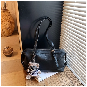 Dettaglio della borsa in pelle nera con ciondolo a forma di orsetto e occhiali vintage