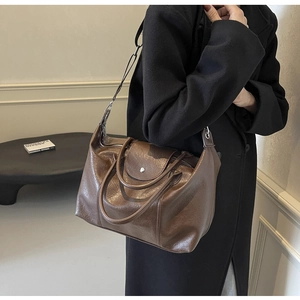 Side view of brown leather tote bag with silver buckle and adjustable shoulder strap