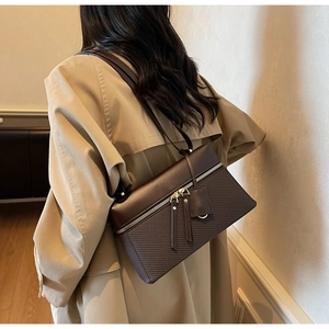 Detail of dark brown leather handbag with mesh texture and double metal zippers