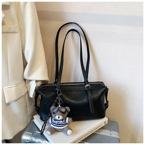 Dettaglio di una borsa bowling in pelle nera su bagaglio con un simpatico ciondolo a orsetto