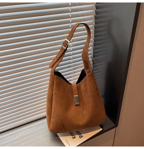 Detail shot of brown suede bucket bag featuring silver metal buckle and adjustable strap