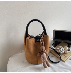 Detail of brown matte bucket bag with cute rabbit charm and metal magnetic closure
