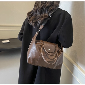 Close-up of retro brown large-capacity tote bag with shiny oil skin texture and broad strap