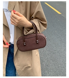 Dettaglio di una borsa Boston in camoscio marrone scuro a forma di pillola con manici