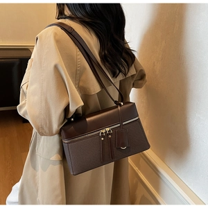 Detail of a dark brown crossbody bag featuring dual texture stitching and gold hardware