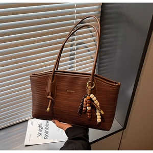 Detailed view of dark brown woven tote bag with colorful bead tassel on soft light