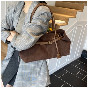 Detalle del bolso tote de pana marrón con correas de cuero y hebilla dorada elegante