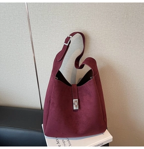 Detail of burgundy suede tote bag featuring adjustable wide strap and silver metal lock