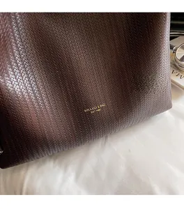 Close-up of dark brown woven texture PU leather tote bag with gold brand lettering