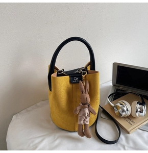 Detail of yellow matte bucket bag showing the logo and a cute bunny plush charm