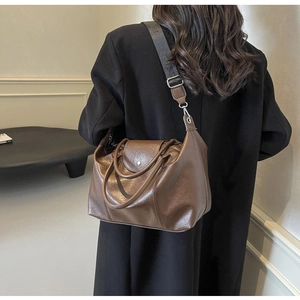 Close-up of brown leather hobo bag with detailed lychee texture and stylish wide strap