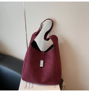 Detailed view of burgundy suede bucket bag featuring a silver rectangular metal clasp