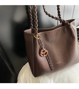 Close-up of dark brown woven tote bag featuring a decorative heart knot pendant detail