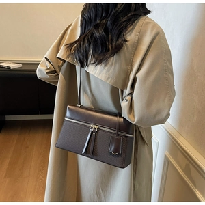 Detail of dark brown leather tote bag with weave texture and long tassel zip on beige coat