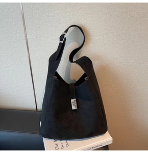 Detail of black suede bucket bag featuring silver buckle and adjustable shoulder strap