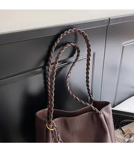 Detail of dark brown woven tote bag with dual braided straps and metal ring decor