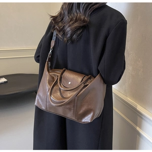 Rear view of a model wearing a dark brown vintage tote bag with metal buckle detail