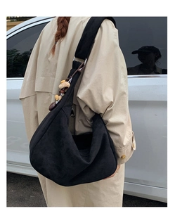 Détail du grand sac hobo noir avec breloque ethnique en perles sur la bandoulière