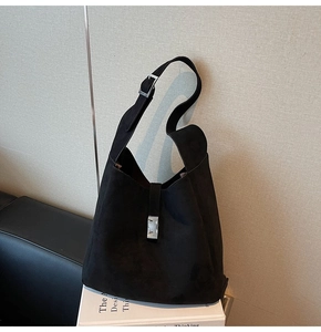 Detail of minimalist black matte suede bucket bag featuring a silver rectangular metal buckle