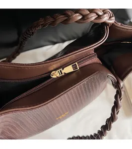 Close-up of golden zipper hardware and woven handle detail on dark brown tote bag