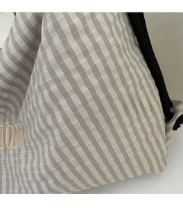 Detail showing grey and white striped fabric texture with gold ION letter embroidery