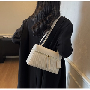 Detail of cream shoulder bag featuring woven texture and smooth leather patchwork
