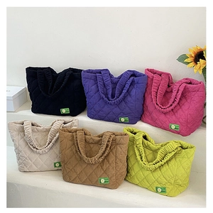 Detailed display of quilted tote bags in six colors arranged on a white tiered stand