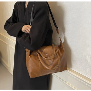Detail view of brown vintage leather tote with adjustable wide strap and magnetic closure