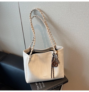Detail of white textured tote bag with woven strap and decorative dessert charms