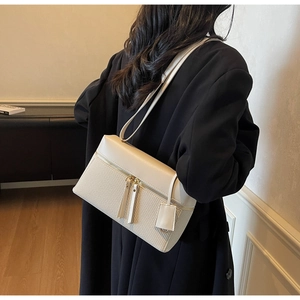 Detailed back view of a beige woven leather shoulder bag styled on a female model