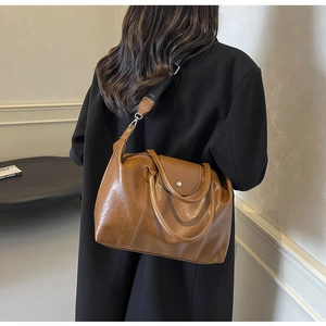 Detail view of the brown leather tote bag with wide strap and polished metal buckle clasp