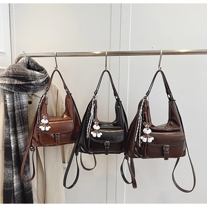 Trois sacs hobo rétro en simili cuir caramel, noir et café avec des breloques en peluche