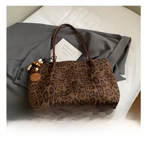 Dettaglio della borsa tote leopardata con manici in pelle marrone e ciondolo in legno
