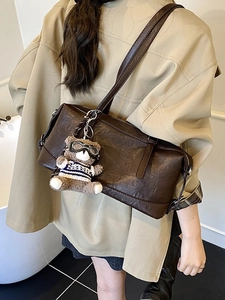 Borsa a tracolla vintage marrone scuro in ecopelle con ciondolo a orsetto su modella