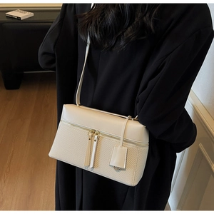 Detail of cream white crossbody bag featuring leather and woven texture mix with zippers