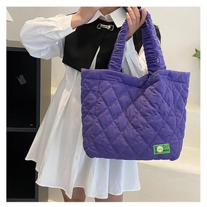 Macro detail of purple quilted tote bag showing fluffy fabric texture and green MISU label
