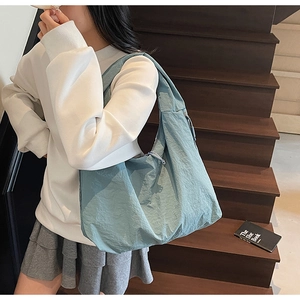 Gros plan sur un cabas en nylon bleu clair montrant la texture souple et la bandoulière large