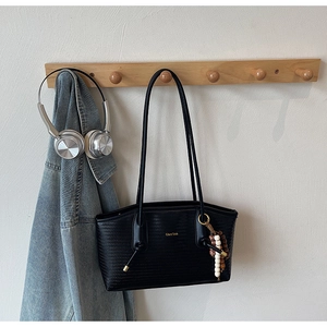 Detailed view of black woven tote bag with gold logo and decorative beaded tassel