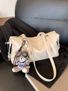 Borsa a bauletto minimalista in pelle beige con ciondolo a forma di orsetto su pelle nera