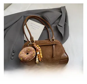 Detail view of vintage brown suede Boston bag with plush donut and wooden bead charms