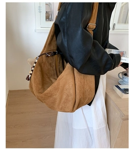 Détail d'un sac hobo en daim marron avec breloque en perles de bois et boucle en métal