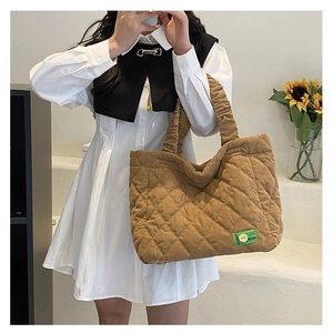 Close-up of quilted brown corduroy tote bag with MISU logo and pleated shoulder strap