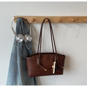 Detailed view of brown woven tote bag featuring decorative beads and silver logo