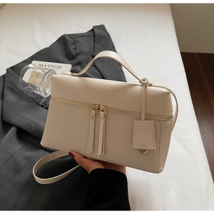Detailed macro view of beige leather bag with woven texture and gold metal hardware