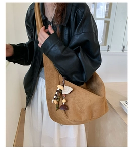 Gros plan du sac hobo en daim marron avec pendentif vintage et bandoulière large