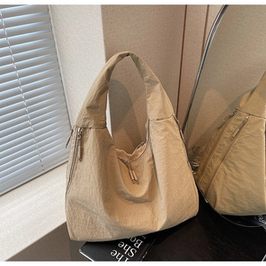 Détail d'un sac cabas en nylon beige avec fermetures éclair et texture plissée moderne