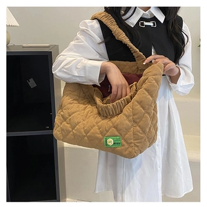 Detail of khaki corduroy quilted tote bag showing soft texture and green logo label