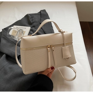 Close-up of beige crossbody bag showing leather and woven texture with twin zippers