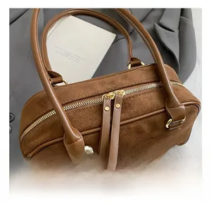 Macro view of gold-tone zippers and matte brown leather texture on Boston bag