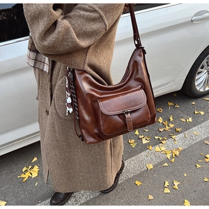 Sac hobo vintage en similicuir marron avec poche à boucle vu de côté et de l'arrière du corps